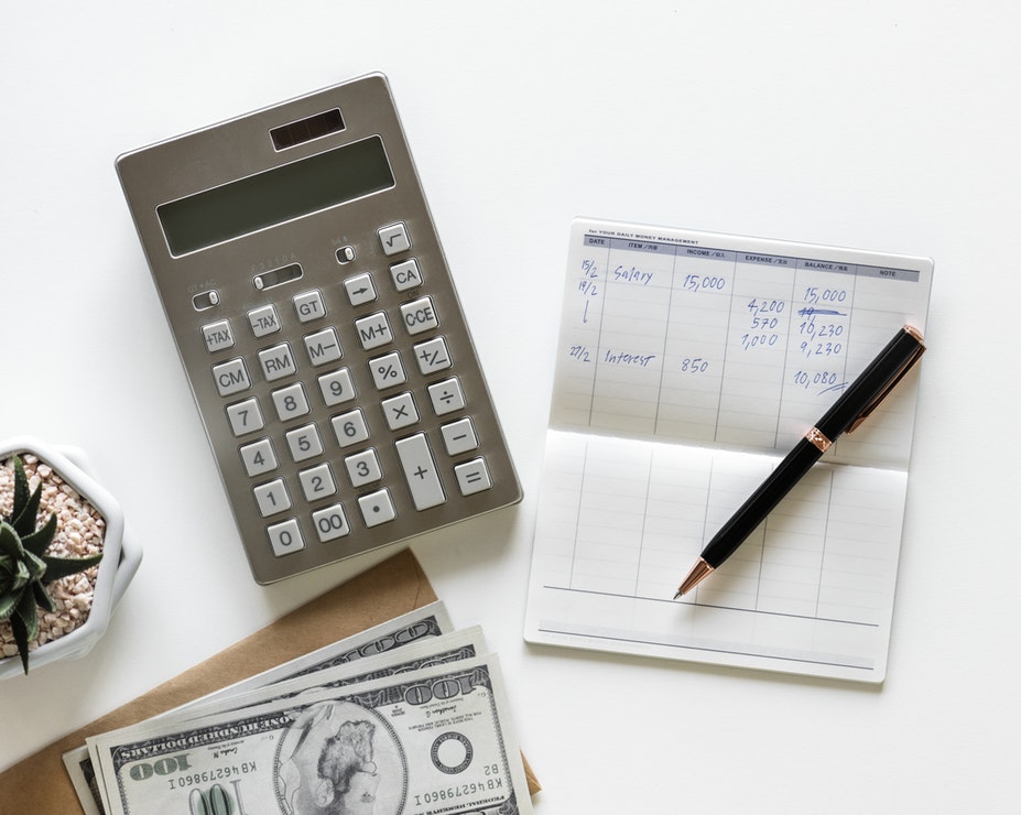Calculator, money and checkbook on a desk.