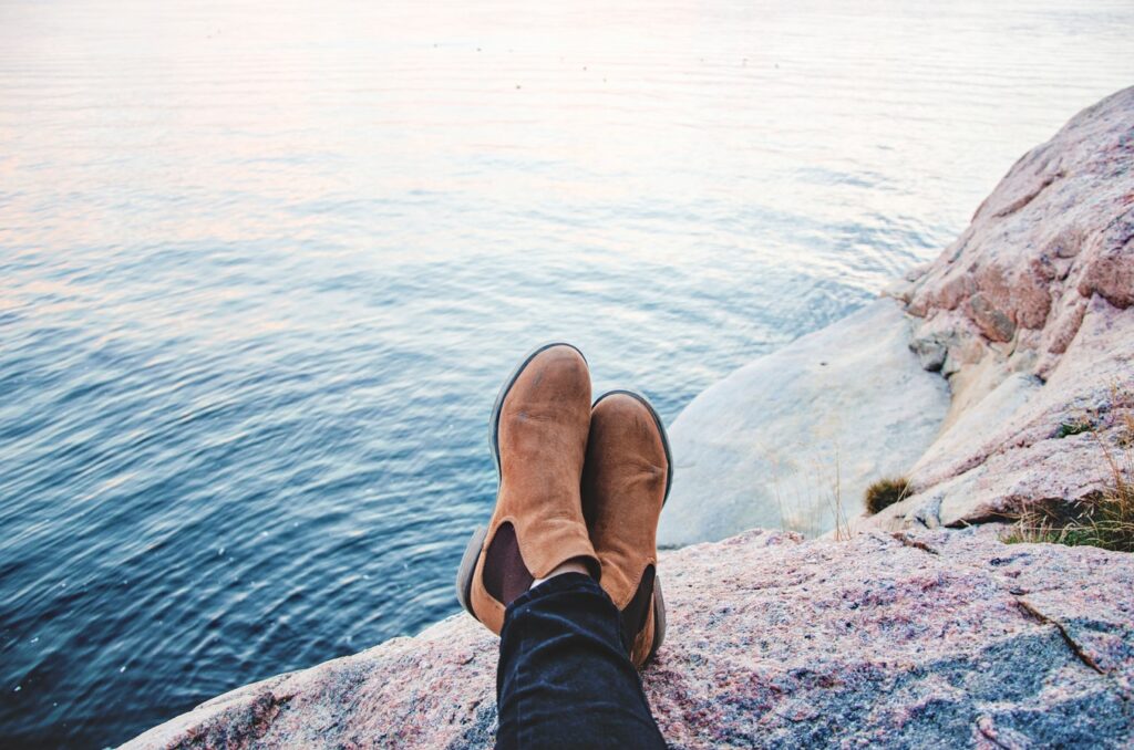 legs crossed with boots overlooking water