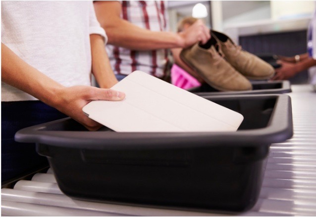 laptop being placed in a bin at airport security checkpoint.