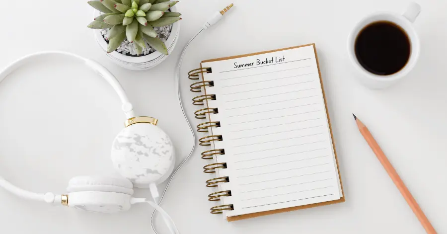 Summer bucket list ideas, notebook with summer bucket list headphones and a cactus on a desk