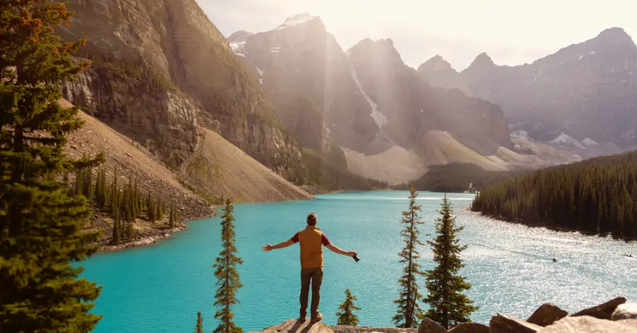 summer bucket list ideas - man standing on a rock looking out over a lake