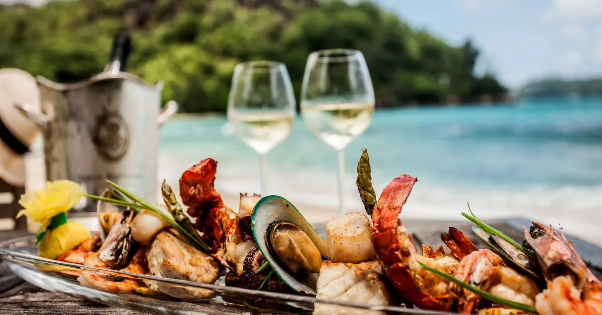 GLUTEN FREE TRAVEL CABO SAN LUCAS - grilled seafood platter, white wine with tropical water and beach in the background