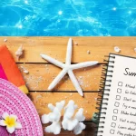 SUMMER BUCKET LIST IDEAS - HAT, SHELLS, AND SUMMER BUCKET LIST NEXT TO A POOL