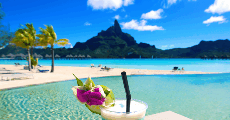 Tropical drink with a view of the beach, ocean and mountain behind it